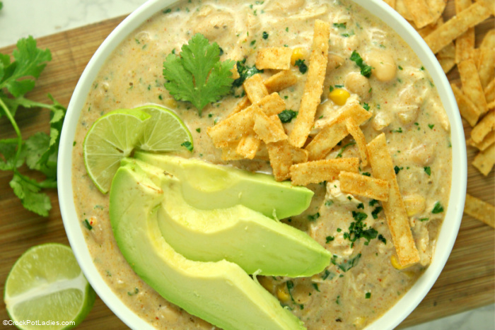 Creamy white chicken chili in a crock pot topped with avocado and cilantro